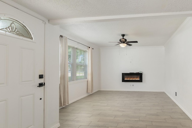 unfurnished living room featuring ceiling fan, a glass covered fireplace, baseboards, light wood-type flooring, and a textured ceiling