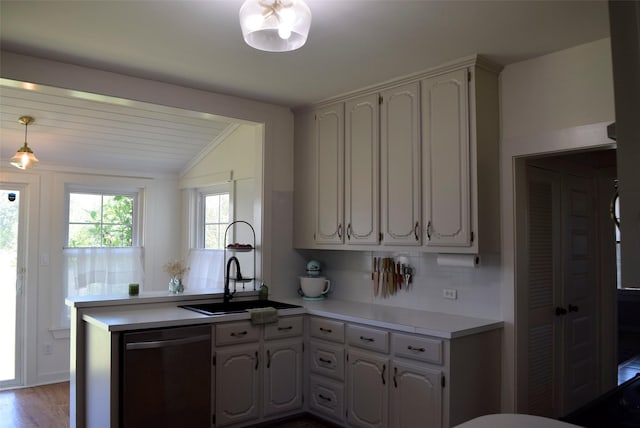 kitchen with a peninsula, light countertops, a sink, lofted ceiling, and dishwasher