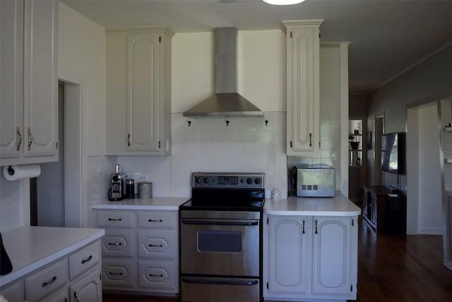kitchen featuring stainless steel electric stove, light countertops, dark wood-style flooring, and wall chimney range hood