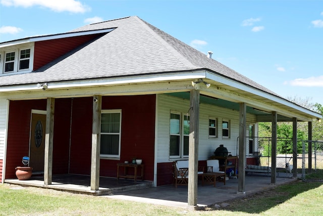 back of house with fence, a shingled roof, and a patio