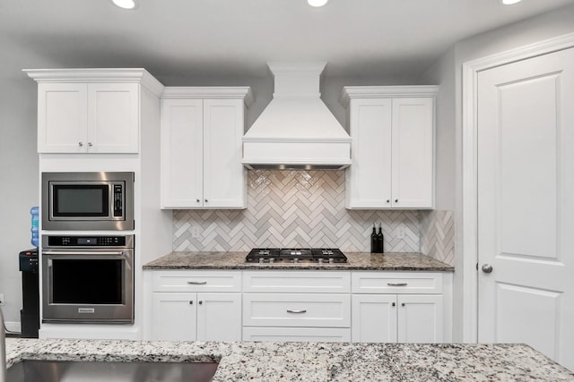 kitchen with custom exhaust hood, backsplash, white cabinets, and stainless steel appliances