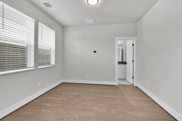unfurnished room featuring light wood-type flooring, visible vents, and baseboards