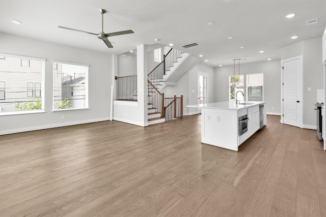 kitchen with a sink, open floor plan, visible vents, and wood finished floors
