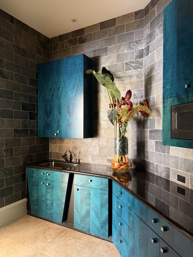 kitchen featuring tile patterned floors, dark countertops, a sink, and blue cabinetry