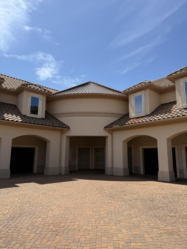 view of front of house featuring a garage, decorative driveway, stucco siding, and a tile roof