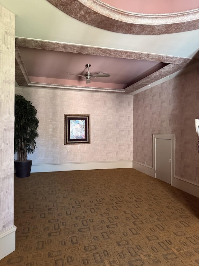 interior space with baseboards, a ceiling fan, and a tray ceiling