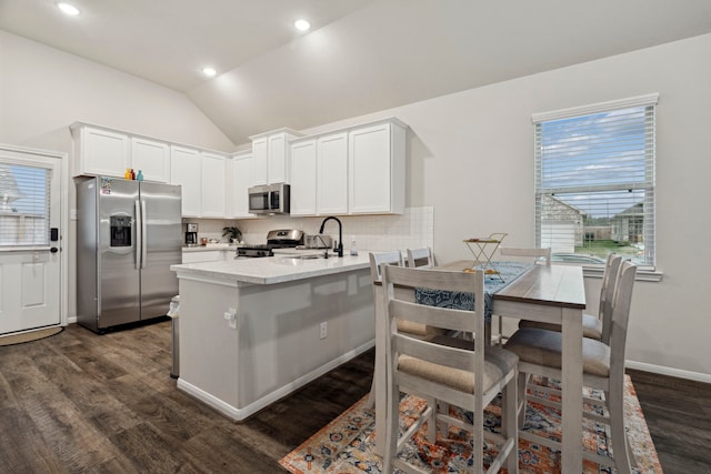 kitchen with a peninsula, backsplash, lofted ceiling, stainless steel appliances, and a sink