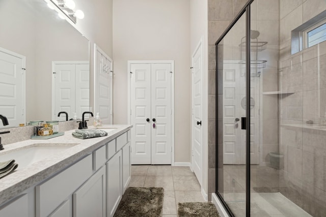 bathroom featuring a closet, a sink, double vanity, tile patterned floors, and a stall shower
