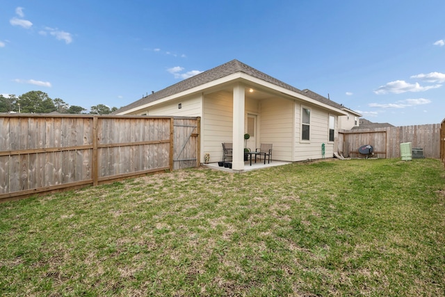 back of house with a fenced backyard, a patio, and a lawn