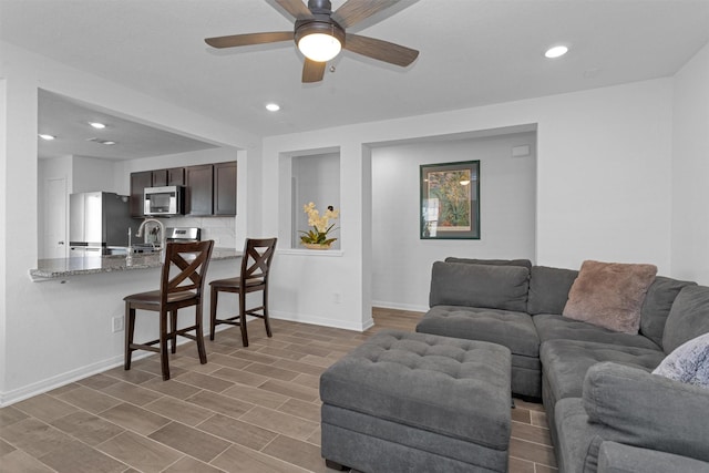 living room featuring baseboards, recessed lighting, ceiling fan, and wood finished floors