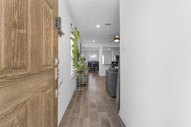 hall featuring visible vents, baseboards, recessed lighting, and wood finished floors
