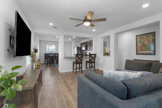 living room with visible vents, baseboards, a ceiling fan, recessed lighting, and light wood-style flooring