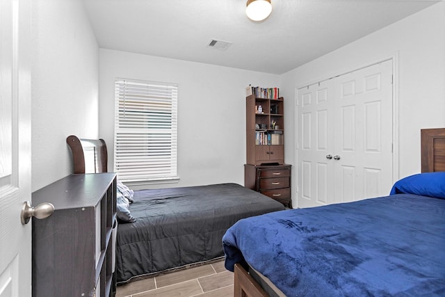 bedroom featuring visible vents, a closet, and wood finish floors