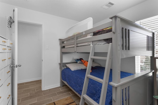 bedroom with visible vents, baseboards, and wood tiled floor