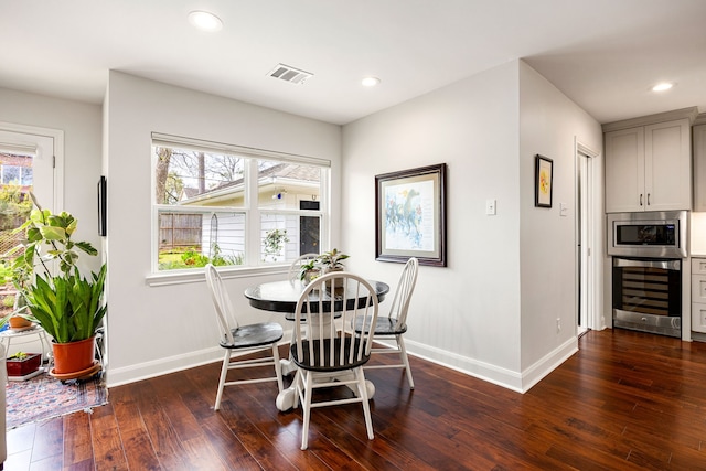 dining area featuring baseboards, recessed lighting, dark wood-style floors, visible vents, and beverage cooler