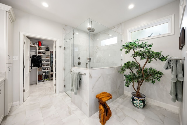 bathroom featuring a spacious closet, recessed lighting, marble finish floor, and a marble finish shower