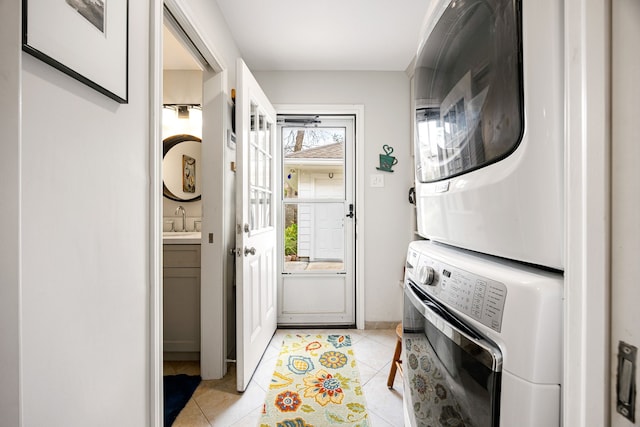 laundry area with stacked washer and dryer, light tile patterned floors, laundry area, and a sink