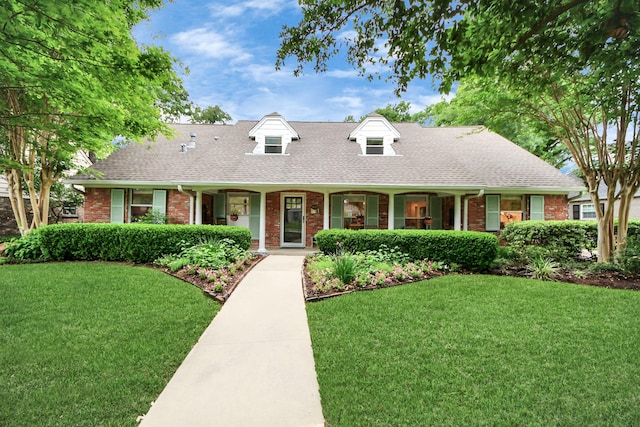cape cod home featuring brick siding, a front lawn, and roof with shingles
