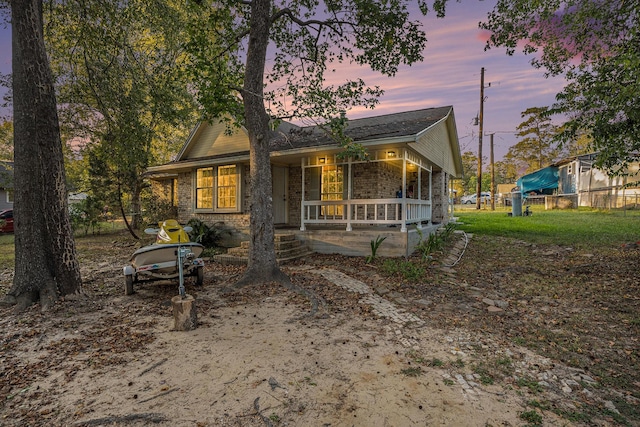 back of property featuring covered porch, fence, and brick siding