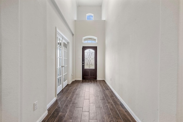 foyer with dark wood-style floors, baseboards, and a high ceiling