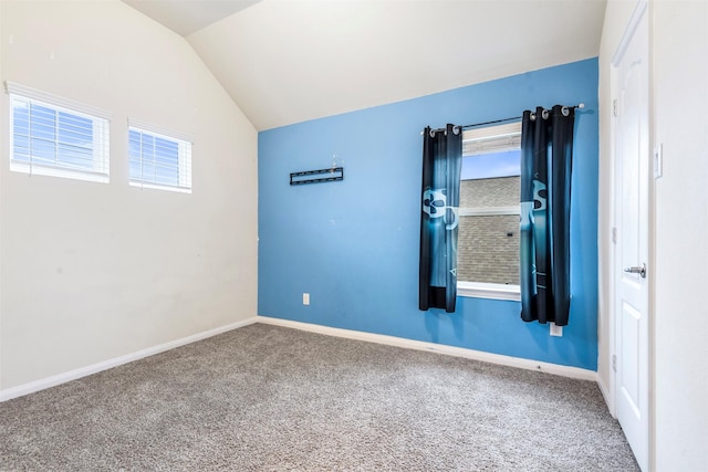 carpeted empty room featuring baseboards and lofted ceiling