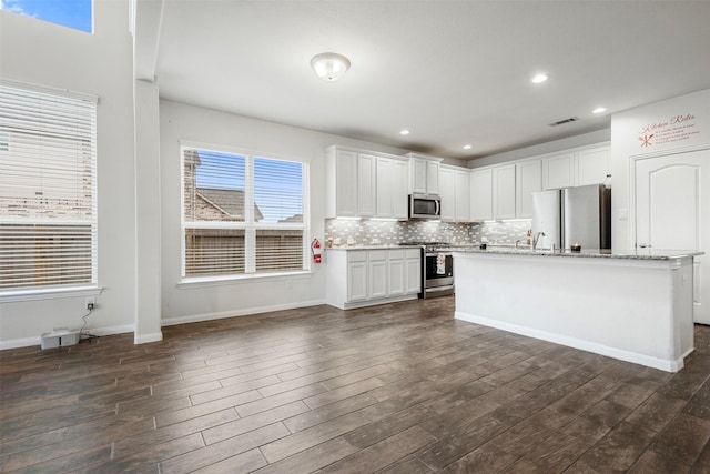 kitchen featuring tasteful backsplash, white cabinetry, appliances with stainless steel finishes, and dark wood finished floors
