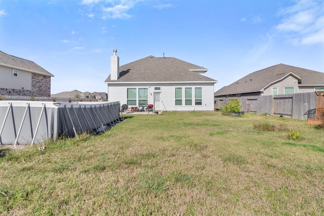 back of property with a patio, a chimney, a pool, a fenced backyard, and a yard