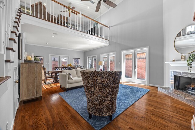 living area featuring wood finished floors, ceiling fan, a high ceiling, and french doors