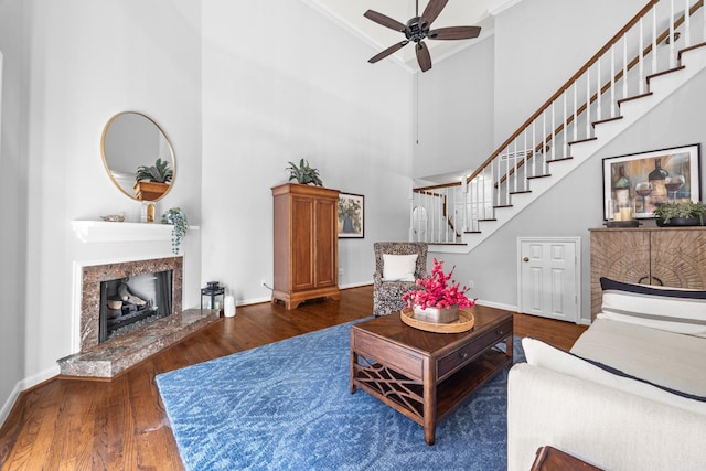 living room featuring stairway, ceiling fan, crown molding, a towering ceiling, and wood finished floors