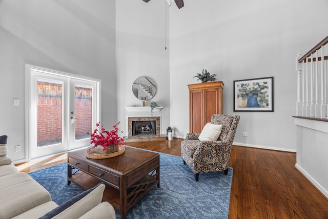 living area featuring baseboards, wood finished floors, a premium fireplace, and a towering ceiling