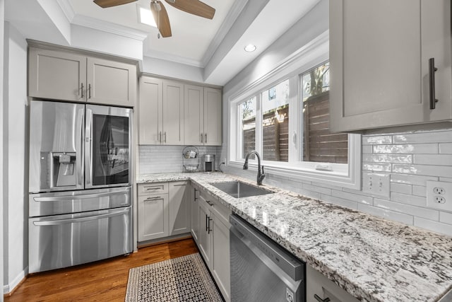 kitchen with ornamental molding, gray cabinetry, a sink, and appliances with stainless steel finishes