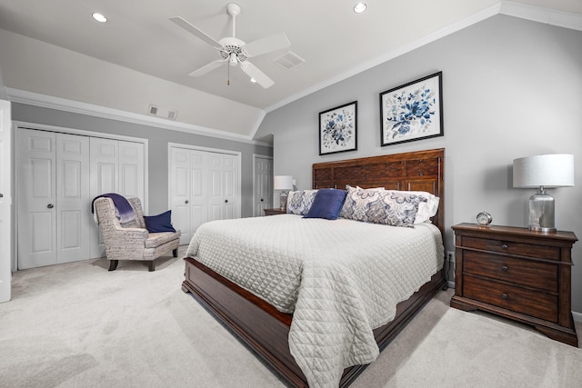 bedroom featuring two closets, lofted ceiling, crown molding, visible vents, and light colored carpet