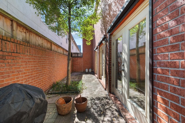 view of side of home with brick siding, fence, and a patio area