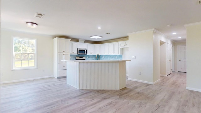 kitchen with visible vents, white cabinets, baseboards, stainless steel appliances, and backsplash
