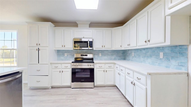kitchen featuring tasteful backsplash, ornamental molding, white cabinetry, light countertops, and stainless steel appliances