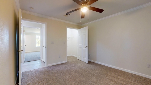 unfurnished bedroom with visible vents, baseboards, ornamental molding, a ceiling fan, and light carpet