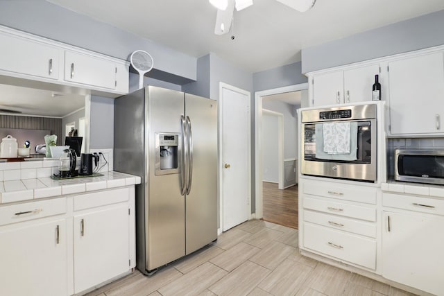 kitchen featuring white cabinets, stainless steel appliances, ceiling fan, and tile countertops