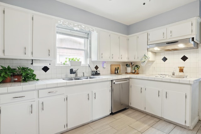 kitchen featuring under cabinet range hood, white cabinets, a sink, and dishwasher
