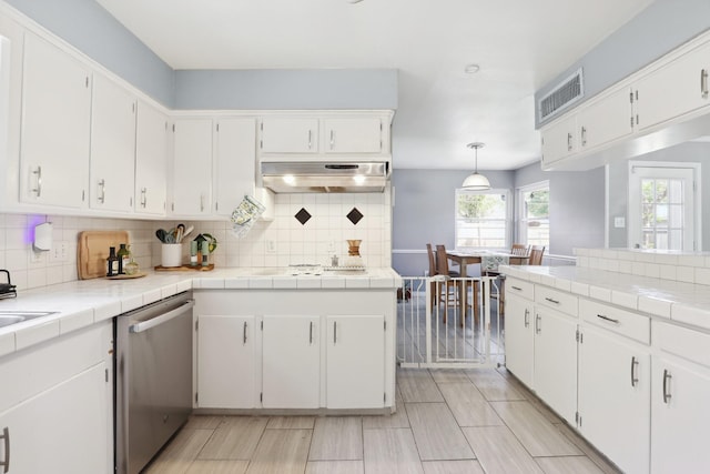 kitchen with white cabinets, under cabinet range hood, tasteful backsplash, and dishwasher