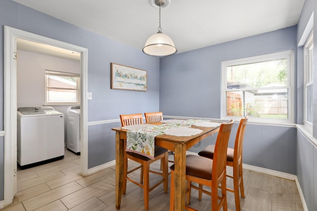 dining area with wood finish floors, washing machine and dryer, and a wainscoted wall
