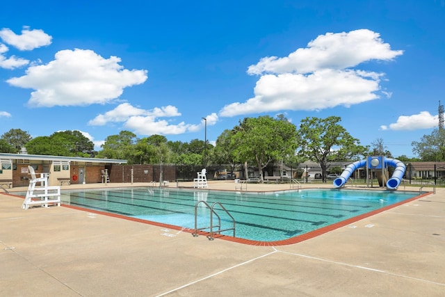 pool featuring a patio, a water slide, and fence