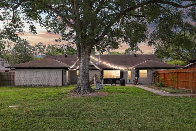 rear view of property with brick siding, fence, a yard, and a patio
