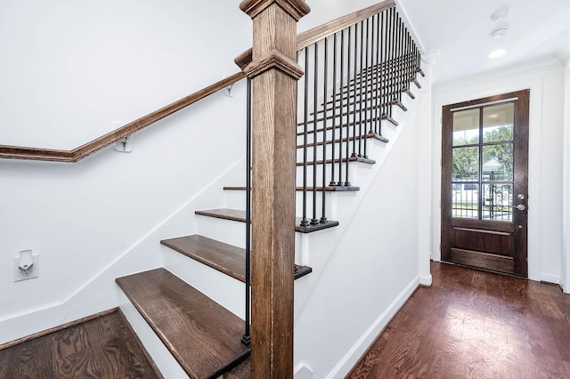 stairway with crown molding, wood finished floors, and baseboards