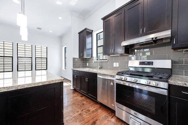 kitchen with ornamental molding, appliances with stainless steel finishes, dark wood-style flooring, a sink, and under cabinet range hood