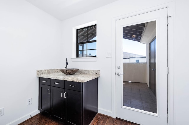 bar featuring a sink, baseboards, and dark wood-style floors