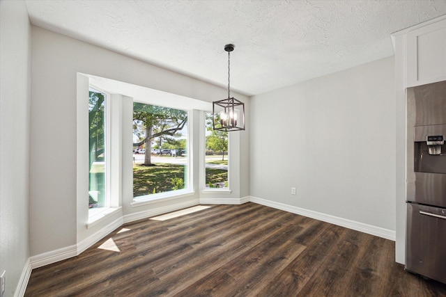 unfurnished dining area with a notable chandelier, baseboards, dark wood-style flooring, and a textured ceiling