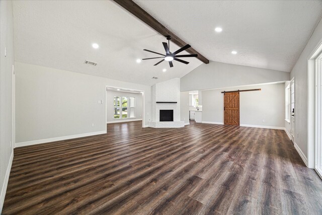unfurnished living room featuring lofted ceiling with beams, dark wood-type flooring, a ceiling fan, visible vents, and a barn door