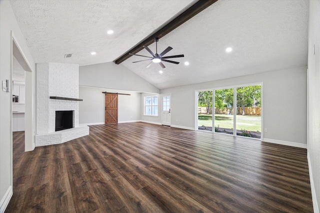 unfurnished living room featuring dark wood-style flooring, ceiling fan, a barn door, and baseboards