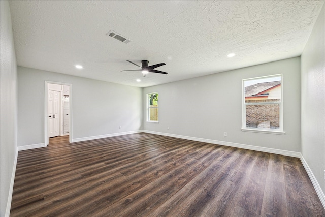 empty room featuring a textured ceiling, baseboards, dark wood-style floors, and visible vents