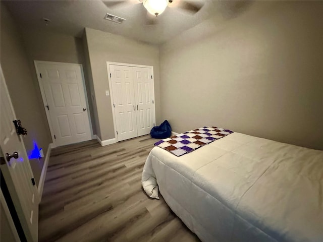 bedroom featuring a closet, baseboards, visible vents, ceiling fan, and wood finished floors
